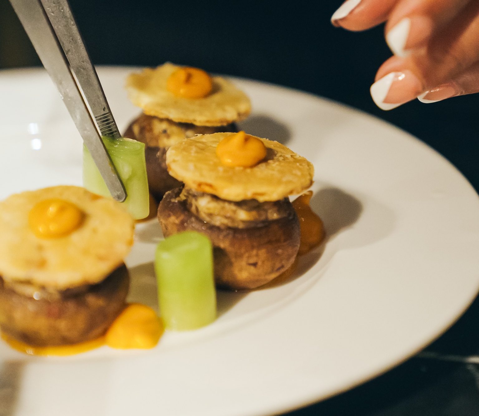 Close-up of a final detail being placed on a row of mushroom canapes.