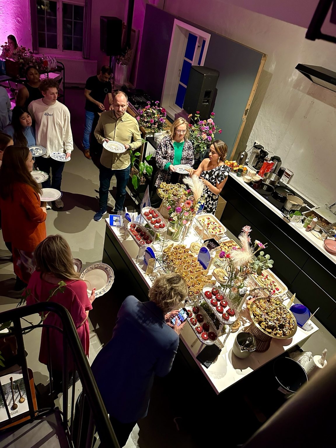 Overhead view of guests gathered around a curated food table at a Nila pop-up event.